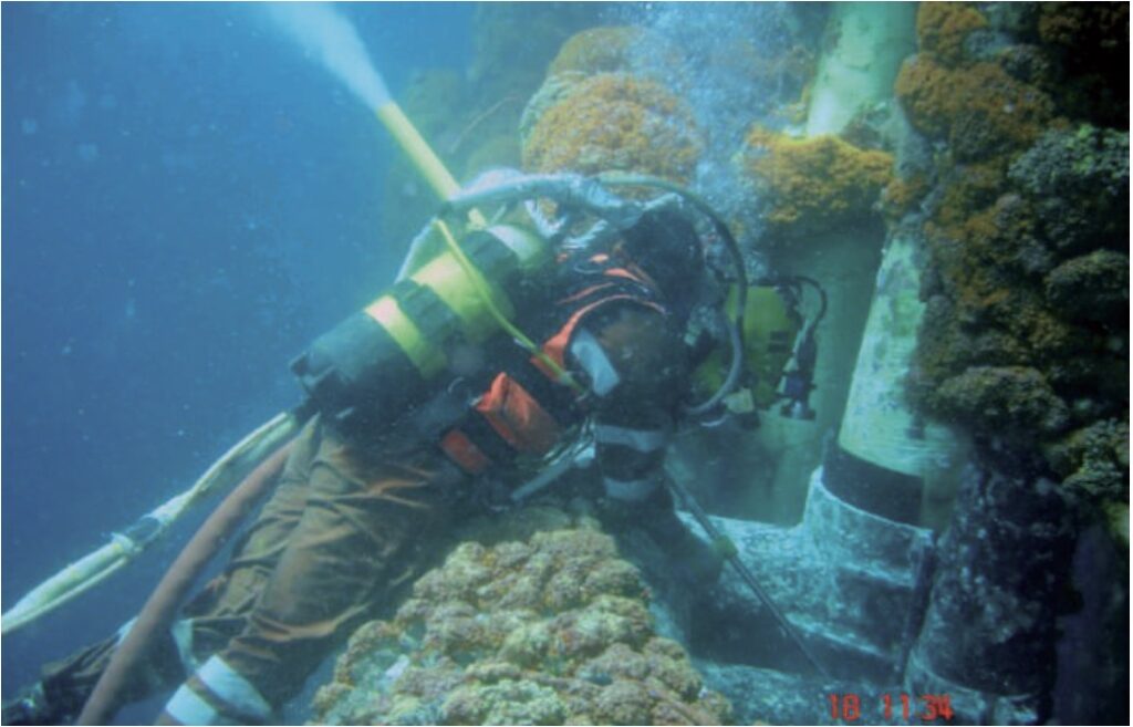 A man removing marine growth underwater